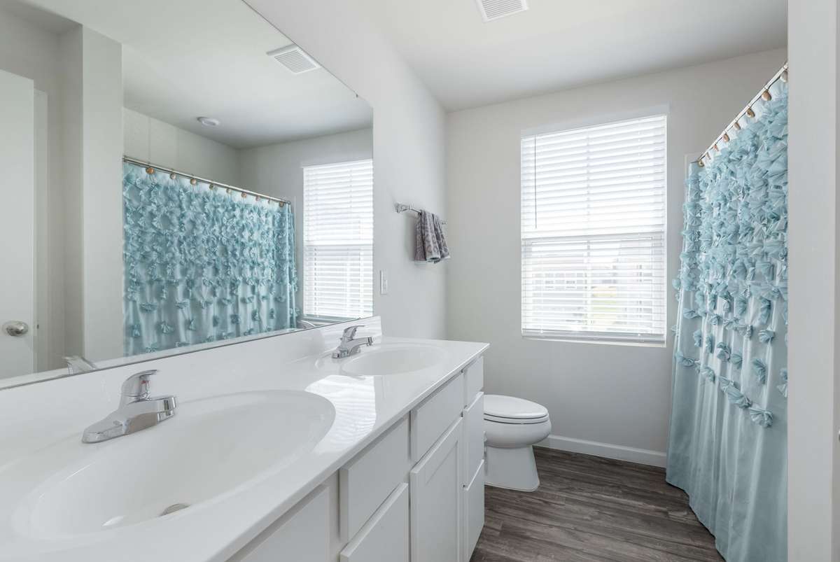 Guest bathroom featuring double sinks and shower/tub combo