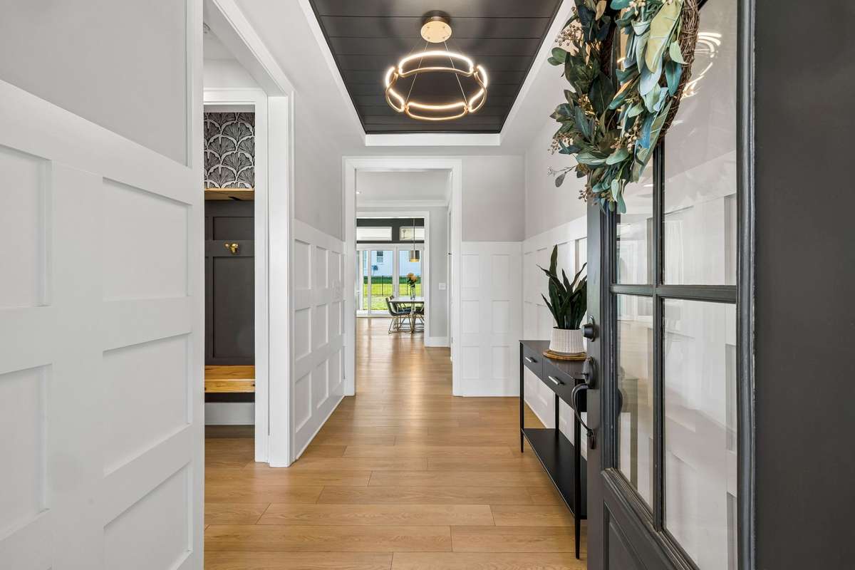 Designer entryway features custom woodwork, upgraded lighting and black shiplap ceiling