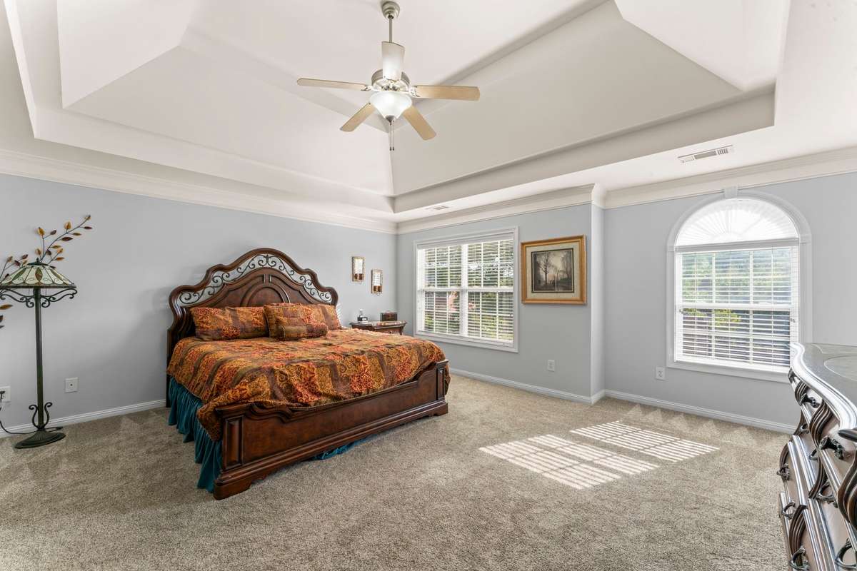 The primary suite has a tall tray ceiling and lots of natural light.