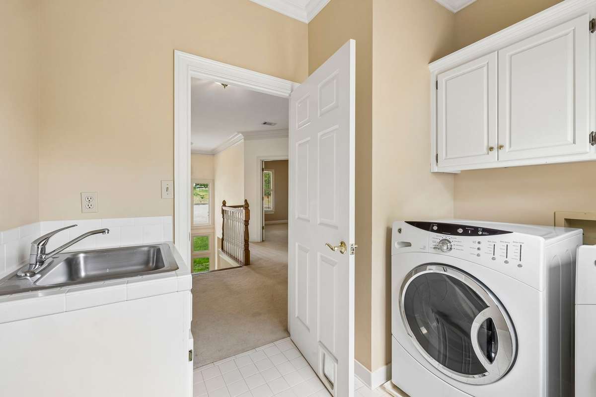 Walk-in laundry room on the second floor with an laundry sink and extra cabinets.