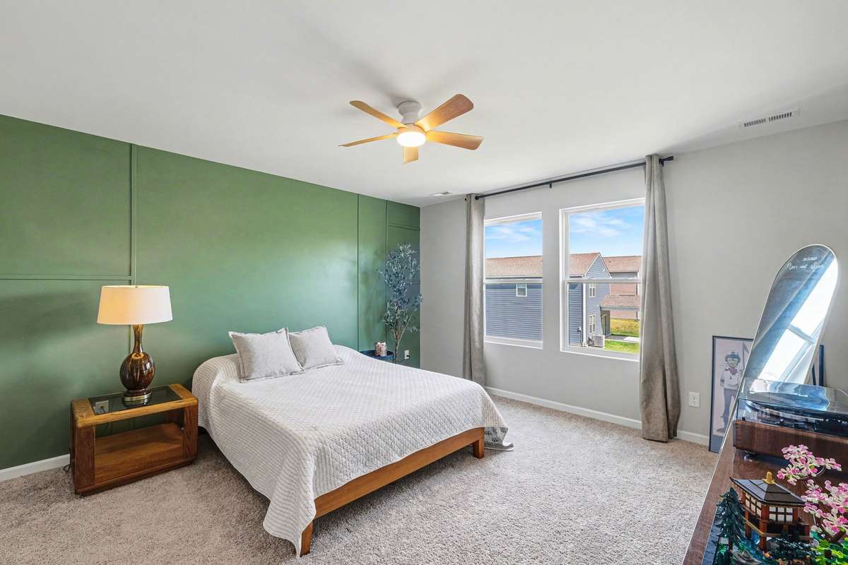 Large primary bedroom, equipped with a ceiling fan and double windows for lots of light