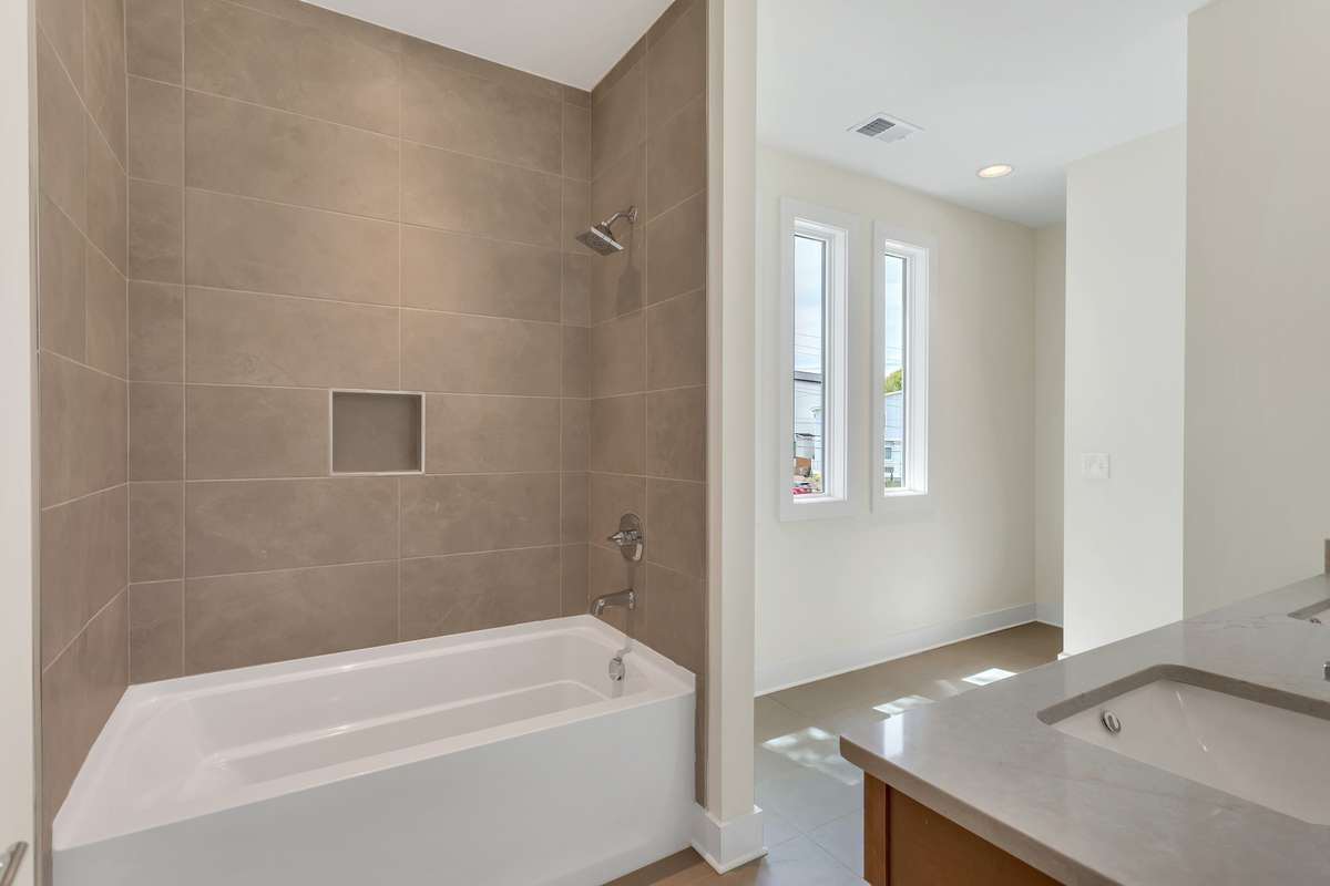 Double vanities, tile to the ceiling, and triple windows give this space a breath of fresh air.
