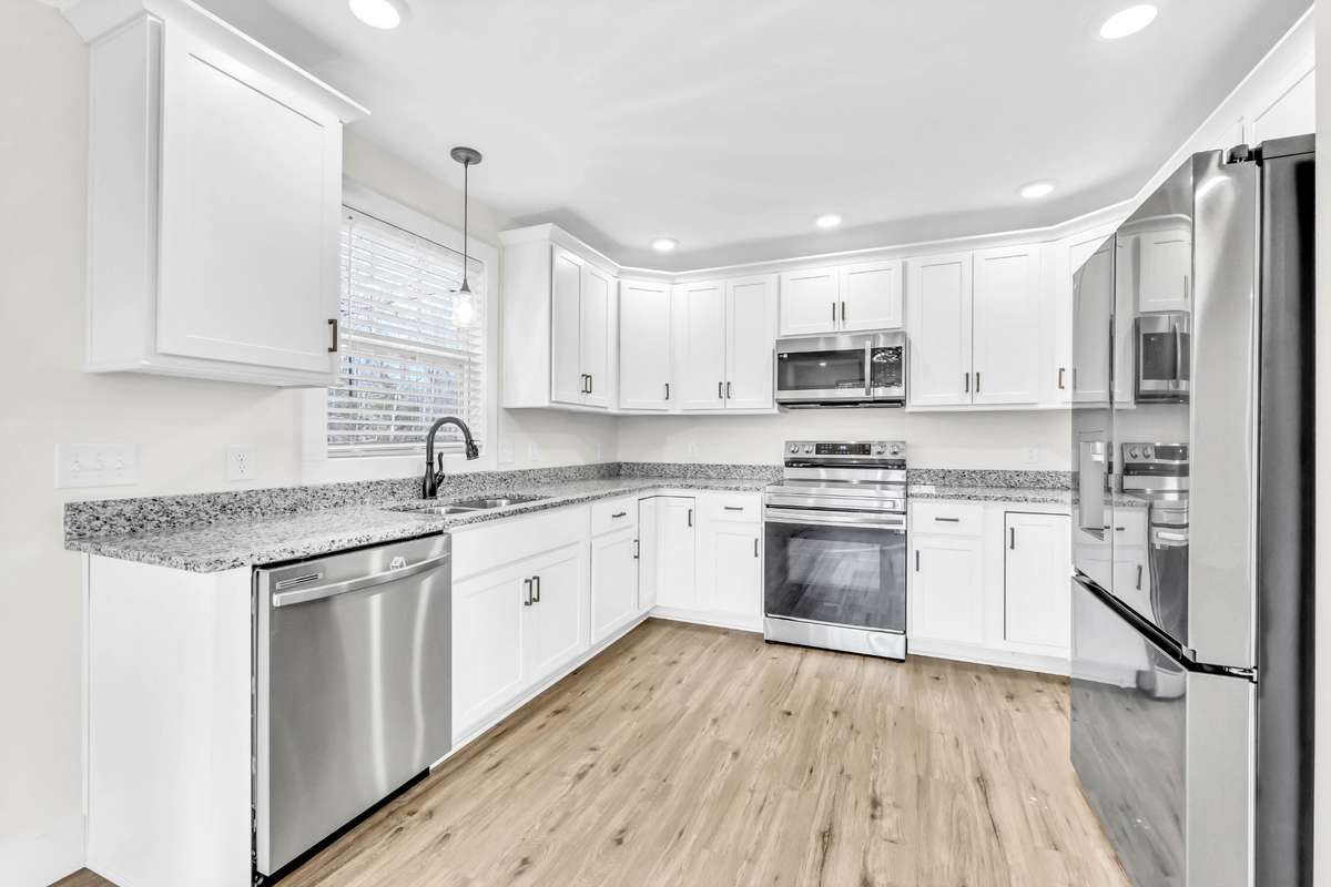 The kitchen offers soft-close cabinets and drawers, a lazy Susan, granite countertops, a pantry, and stainless steel appliances, plus direct access to the covered back deck, making it easy to cook, grill, and entertain.