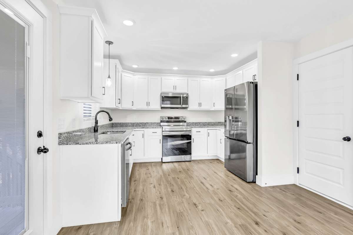 The kitchen offers soft-close cabinets and drawers, a lazy Susan, granite countertops, a pantry, and stainless steel appliances, plus direct access to the covered back deck, making it easy to cook, grill, and entertain.
