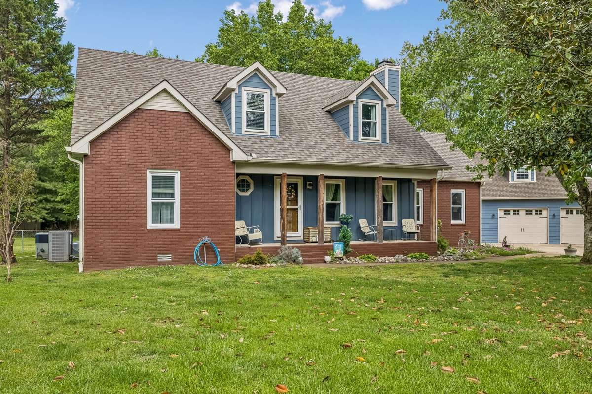 Brick exterior with covered front porch spans the width of the house with room for outdoor seating.