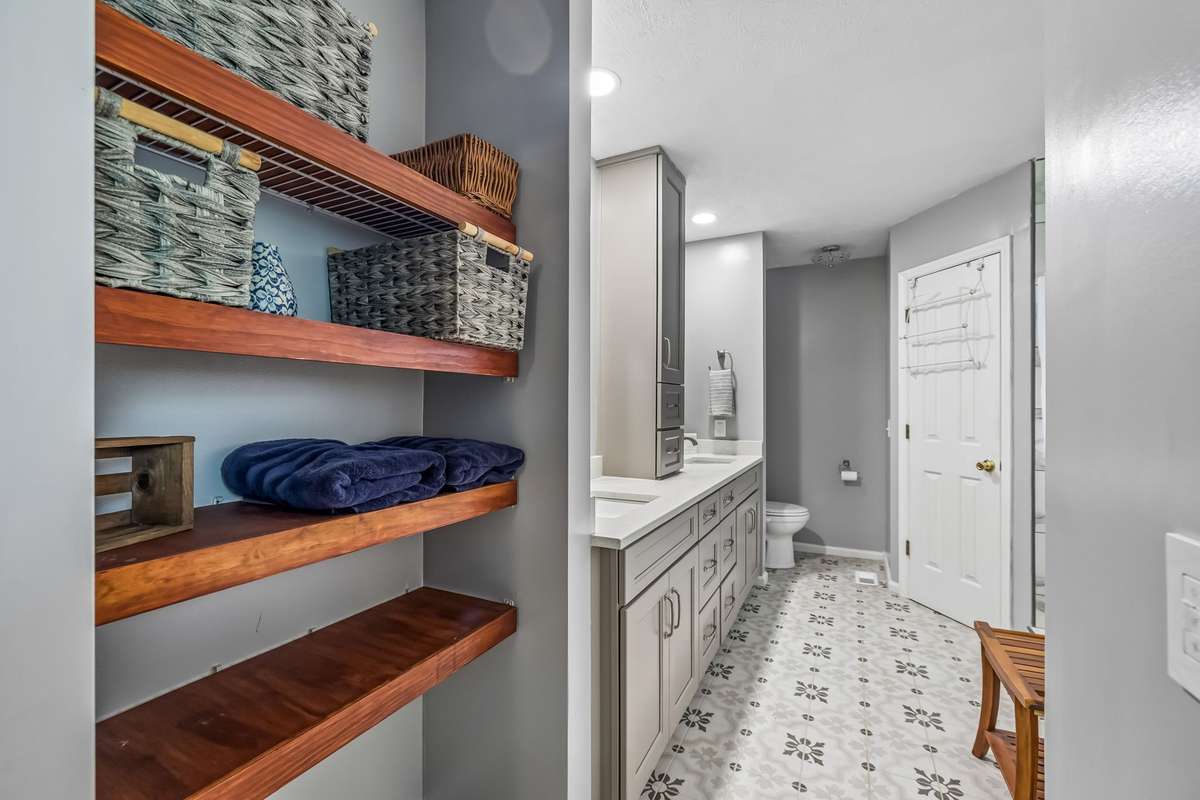 Primary bathroom with built-in shelving, double vanity, and toilet tucked behind the main vanity area.