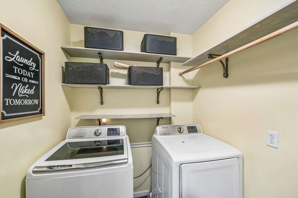 Convenient laundry on the main level with built-in shelving and a hanging rod.