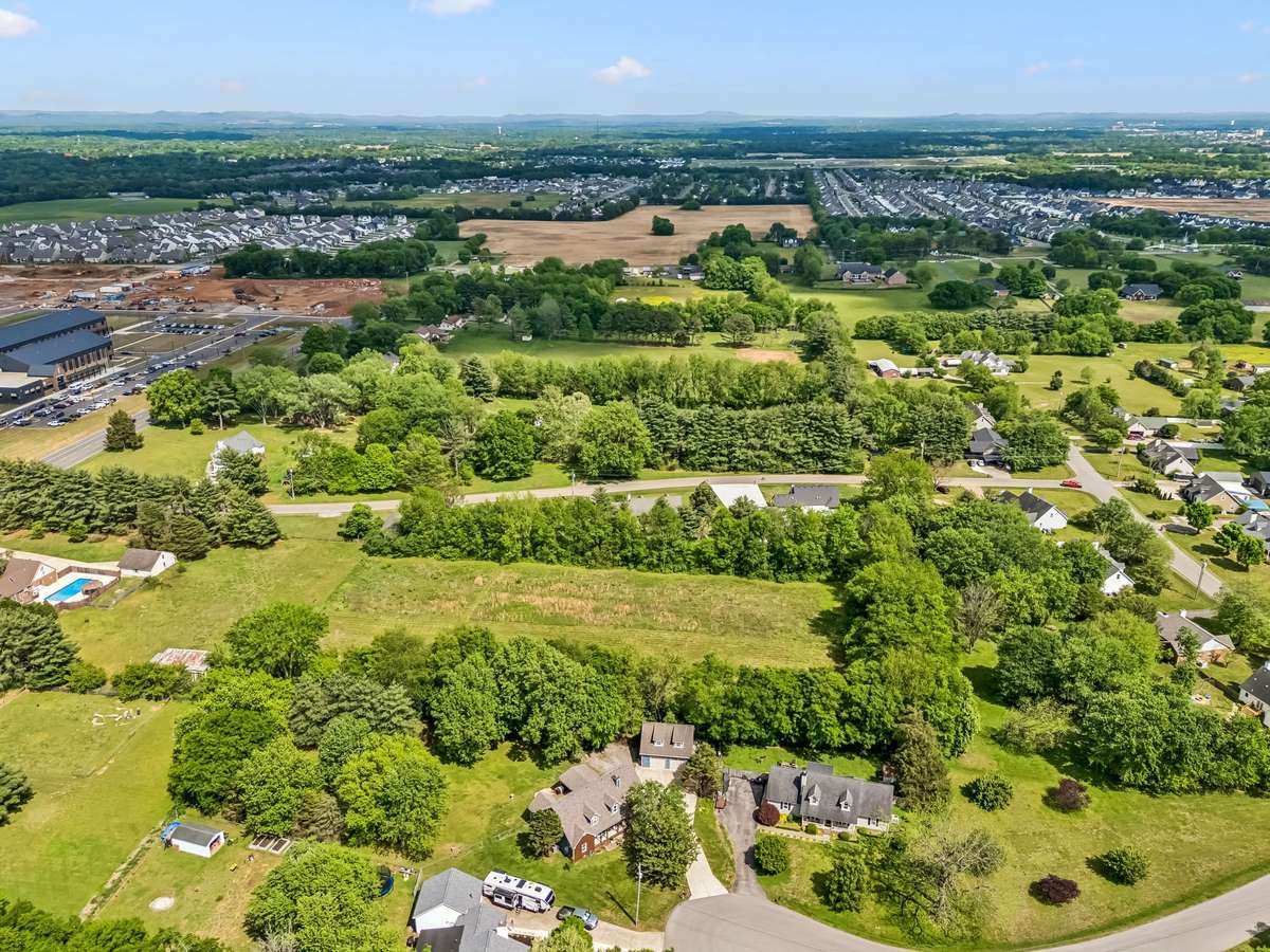 Aerial perspective shows the wooded privacy buffer surrounding this corner lot, tucked away from the neighboring subdivisions but still close to schools and shopping.