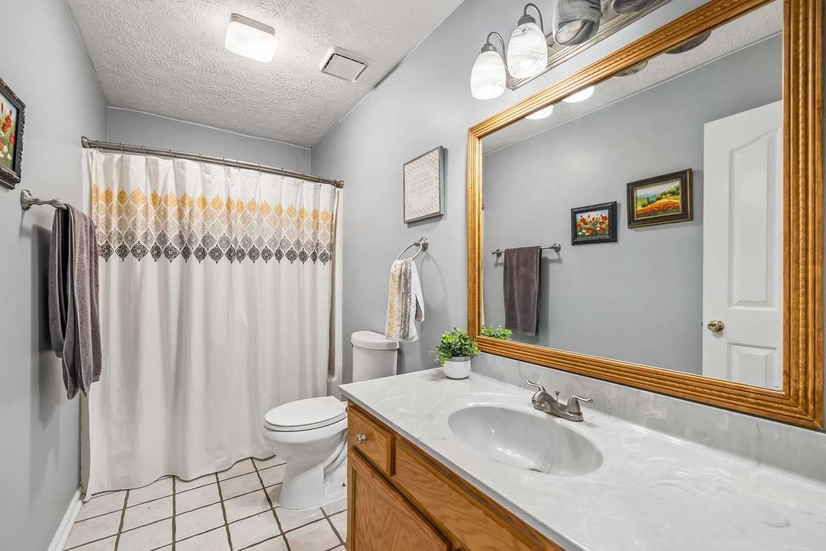 Full bathroom with a tub-shower combo, white vanity, and tile flooring that connects to the hallway through a standard door.