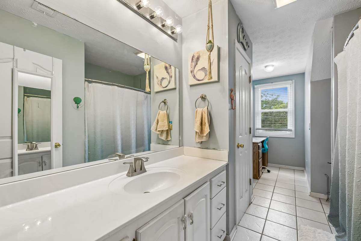 Double vanity with separate tub and shower, plus a hallway connection that keeps the morning routine moving between here and the bedrooms.