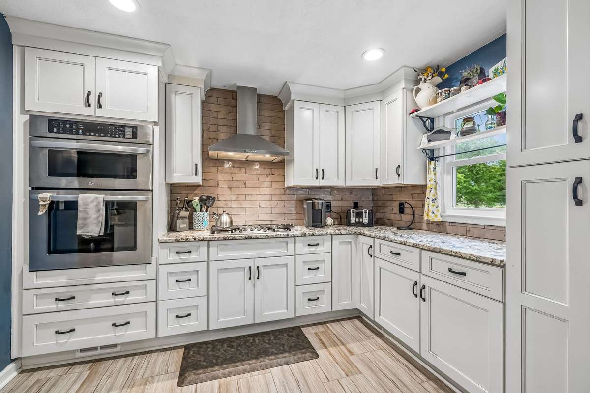 The corner built-in stainless oven and microwave stack keeps everything within reach of the main work zone.