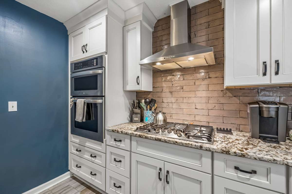 The range fits right into the cooking zone with granite counter and that backsplash extending all the way up to the hood.