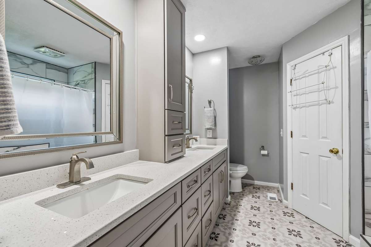 Gray walls and patterned tile flooring give this bathroom an elevated feel.