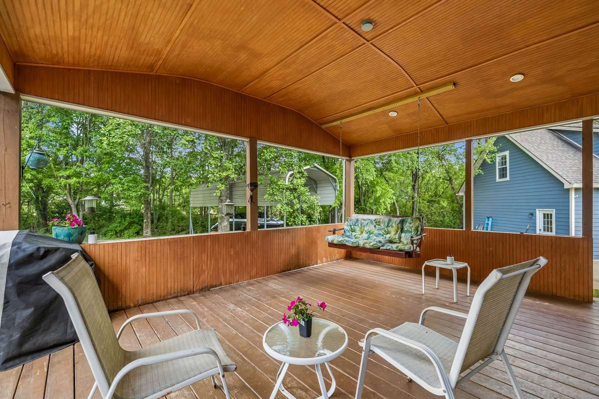 Covered deck with a wood ceiling and recessed lighting overlooks the backyard.