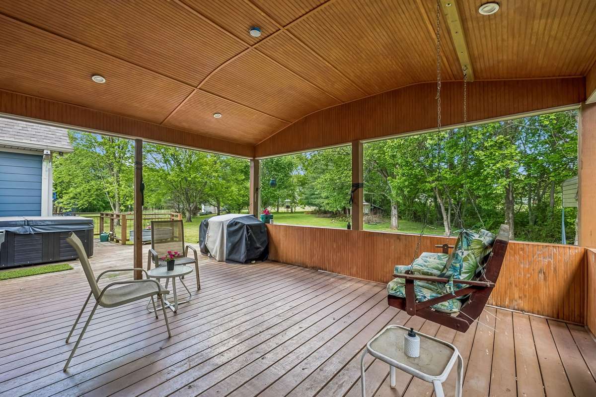 Covered deck with wood ceiling and built-in railing overlooks the fenced backyard, great spot for grilling and relaxing.