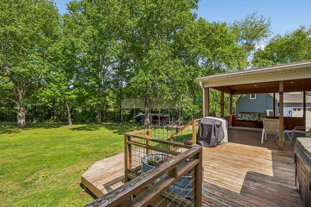 Covered outdoor space flows right off the back of the house with steps down to the fenced yard below.