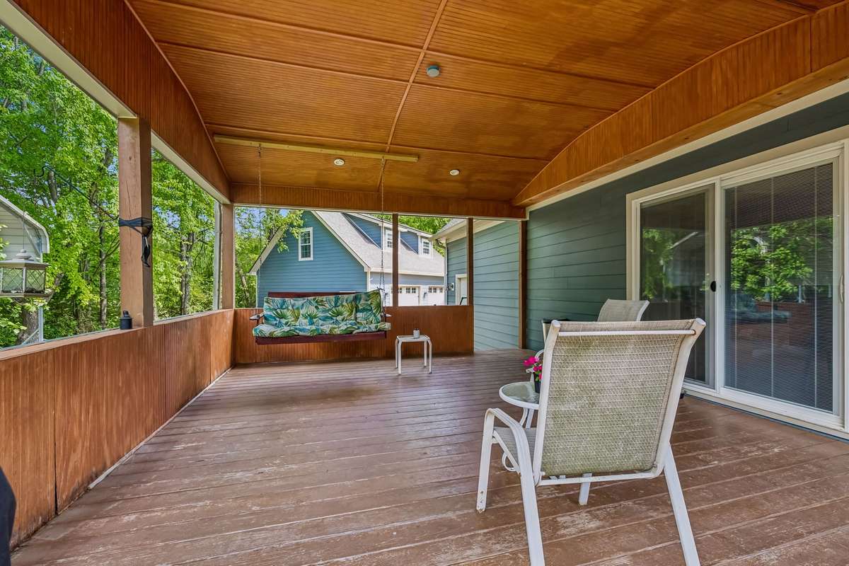 This covered deck wraps around with wood railings and enough room to set up different seating areas.