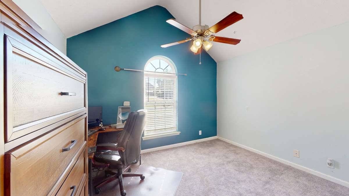 main floor bedroom 3 with a tall ceiling, ceiling fan, and lots of natural light