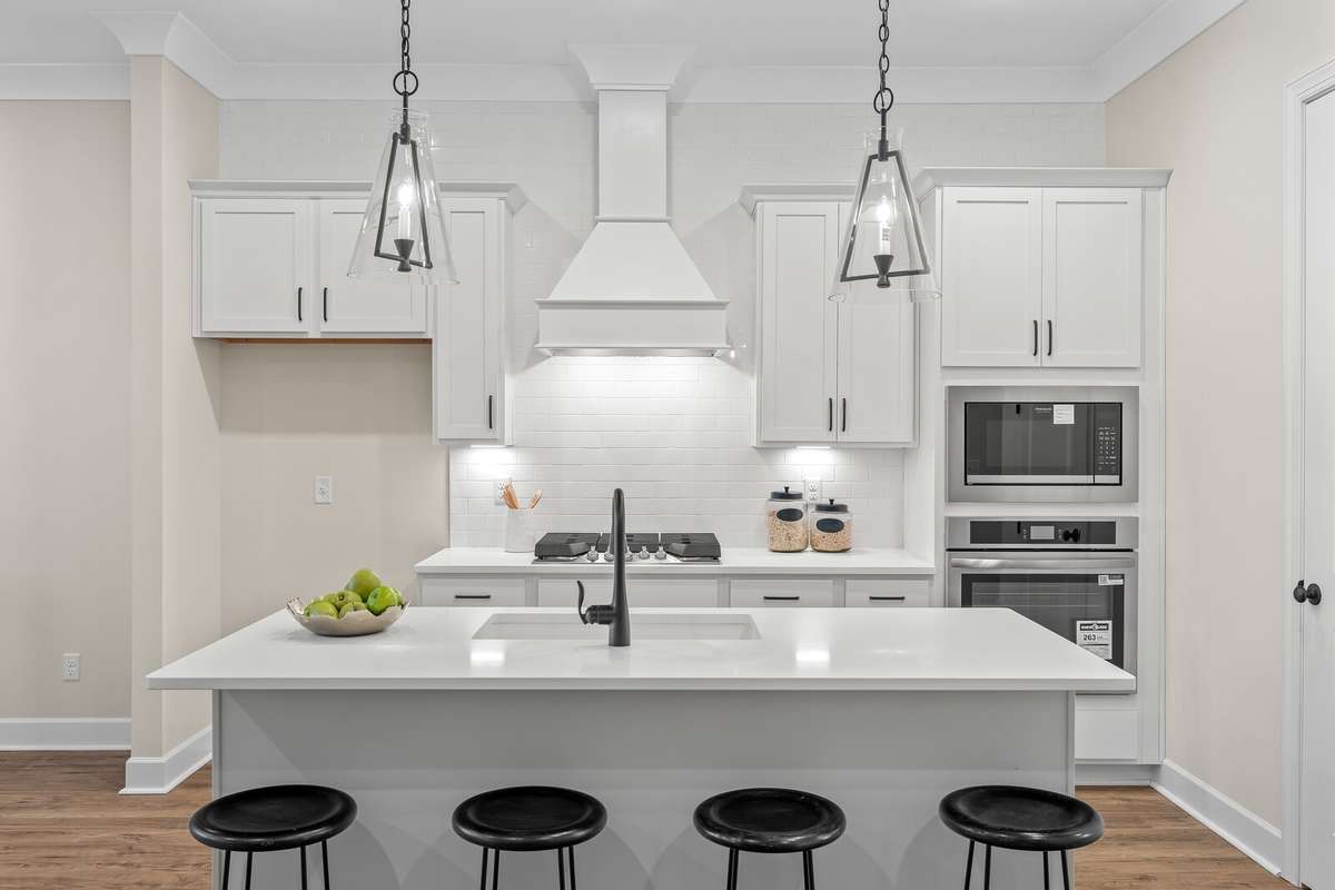 Beautiful kitchen with pendant lighting, under cabinet lighting, tile backsplash and quartz countertops