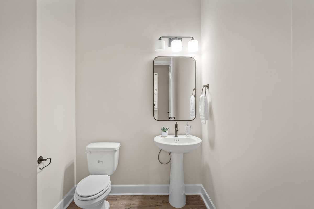 first floor powder room with pedestal sink, designer mirror and lighting.