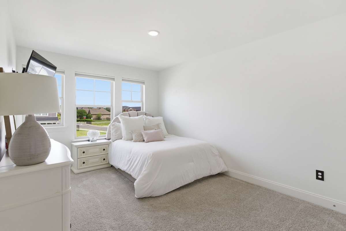 Bedroom 2 features multiple windows that bring in abundant natural light, creating a bright, airy, and open feel