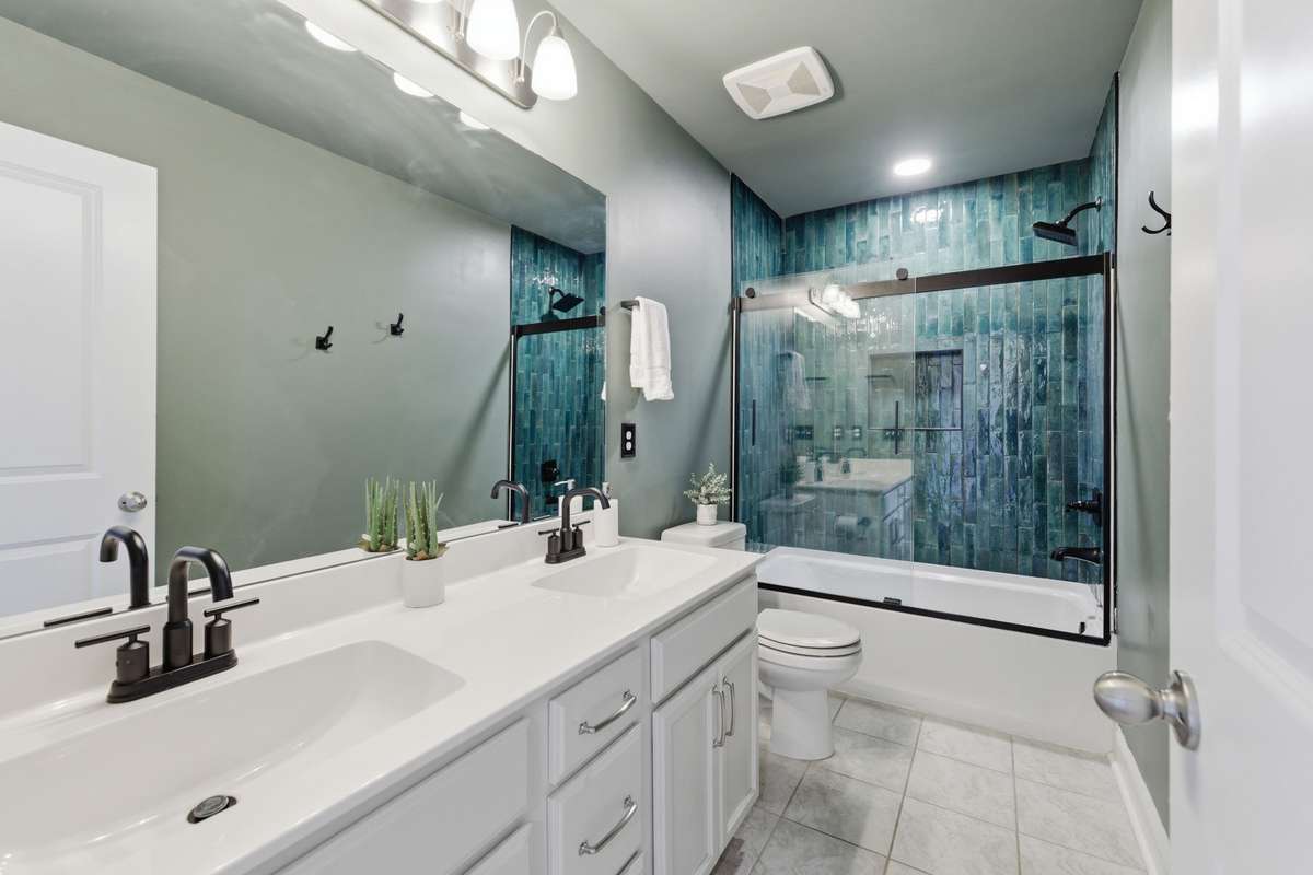 Upstairs guest bath conveniently situated between guest bedrooms, featuring custom tilework and a sleek sliding glass door for a clean, modern touch