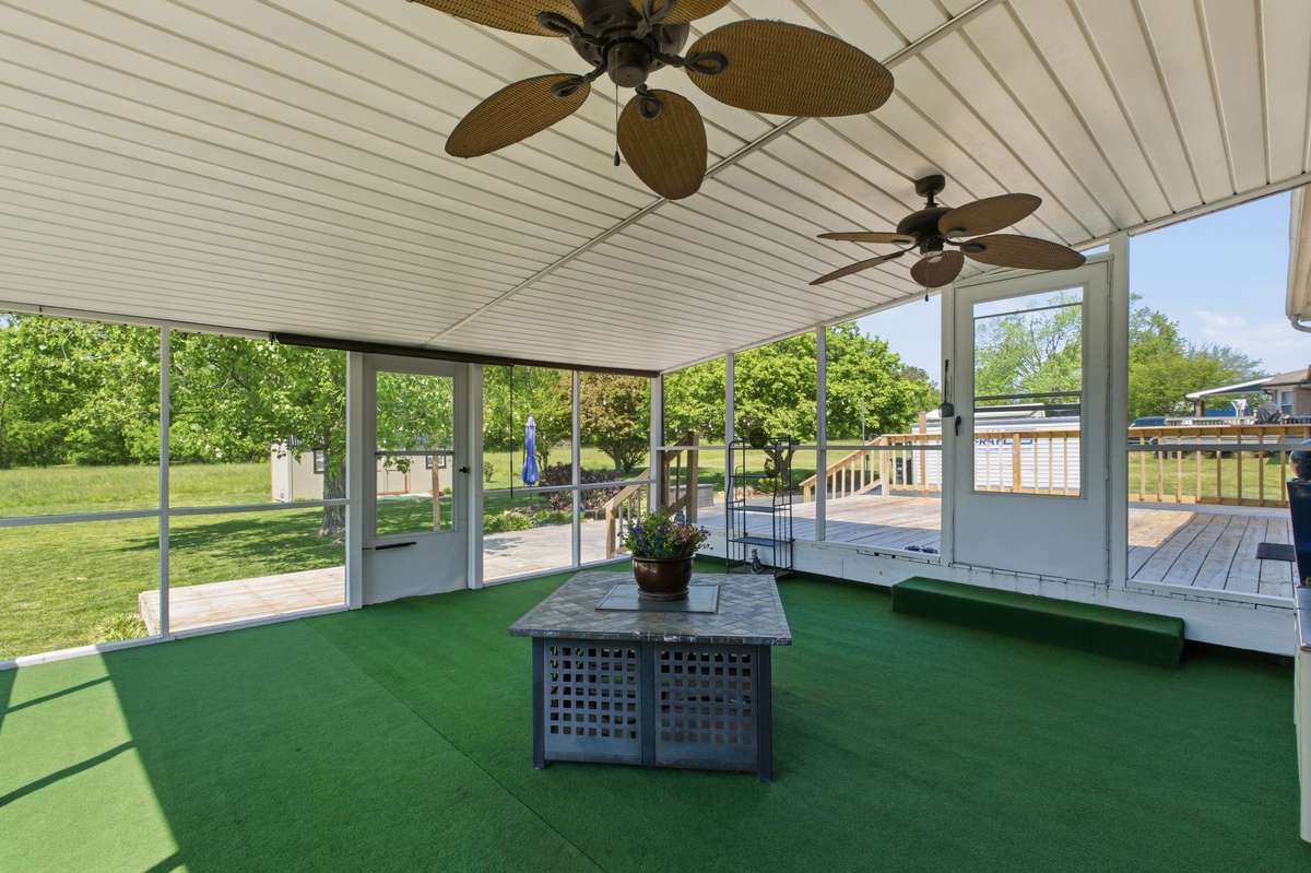 Covered outdoor living with ceiling fans and peaceful backyard views.