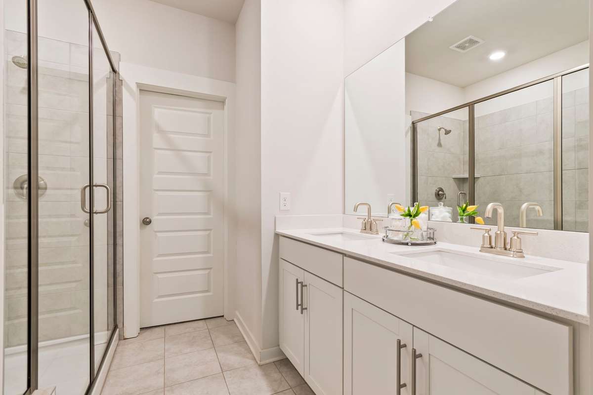 The primary en-suite bath features dual vanities, a walk-in shower with bench, and an oversized walk-in closet.