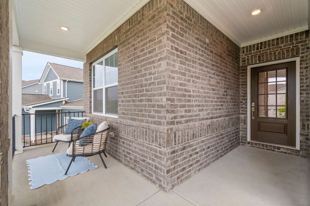 Charming covered front porch with brick exterior and a welcoming entry—an ideal space to relax and enjoy the neighborhood.  Ring doorbell conveys with home.