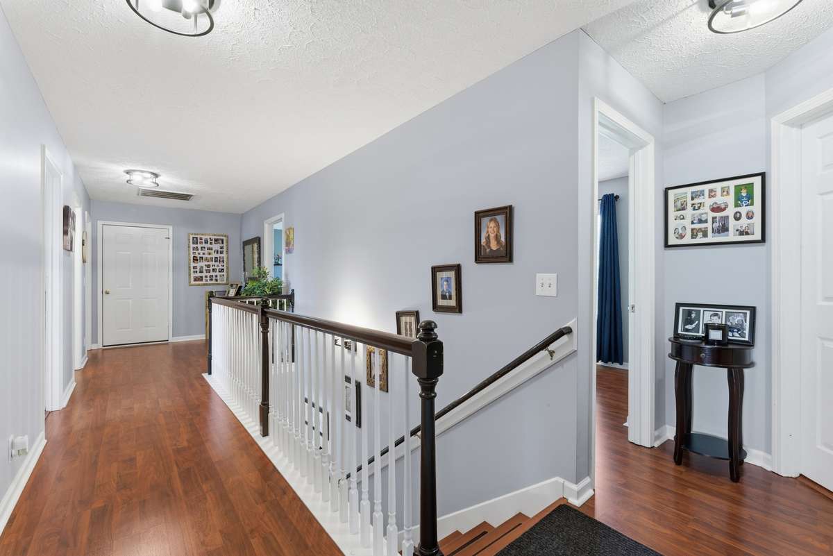 Upstairs hallway with wood floors plus wood staircase. New light fixtures