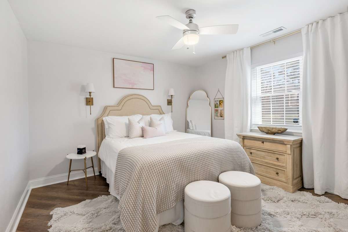 Primary bedroom with ceiling fan, blinds, and decorative curtains