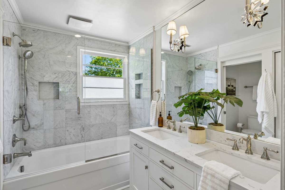 Luxe primary bath featuring double vanities and classic marble tiling throughout the floors and shower.