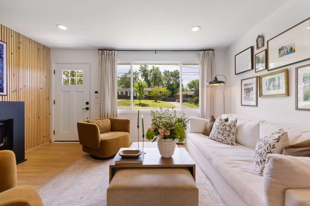 The Living Room includes a stunning wooden acoustic-paneled wall, an electric fireplace, an extra-large picture window, recessed lighting, and hardwood floors.
