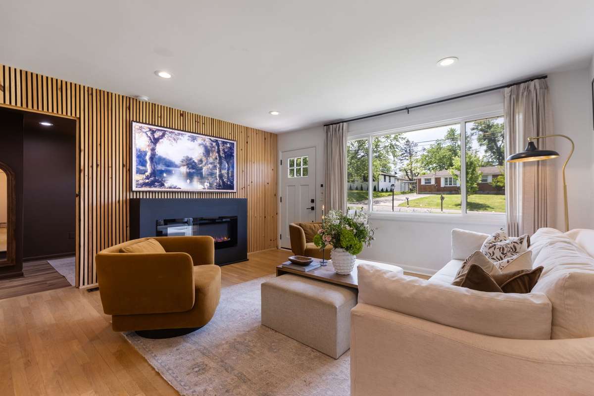 The Living Room includes a stunning wooden acoustic-paneled wall, an electric fireplace, an extra-large picture window, recessed lighting, and hardwood floors.