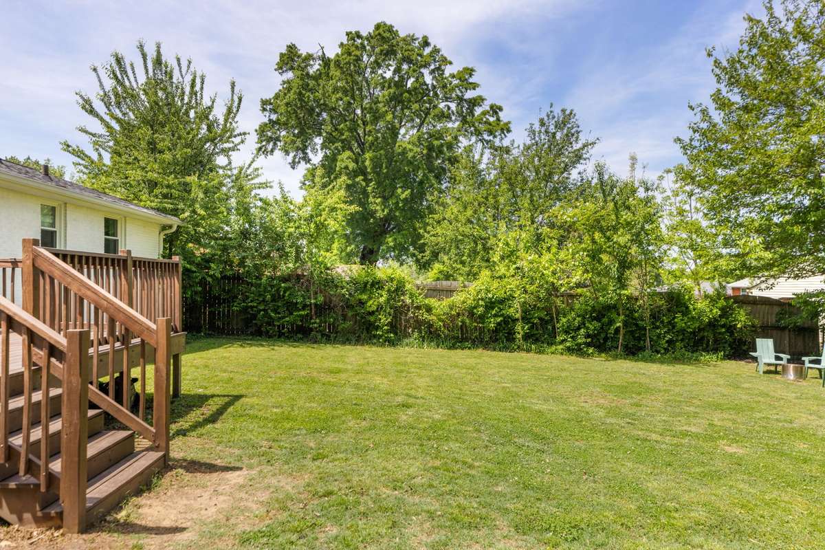 The level backyard backs to mature trees.
