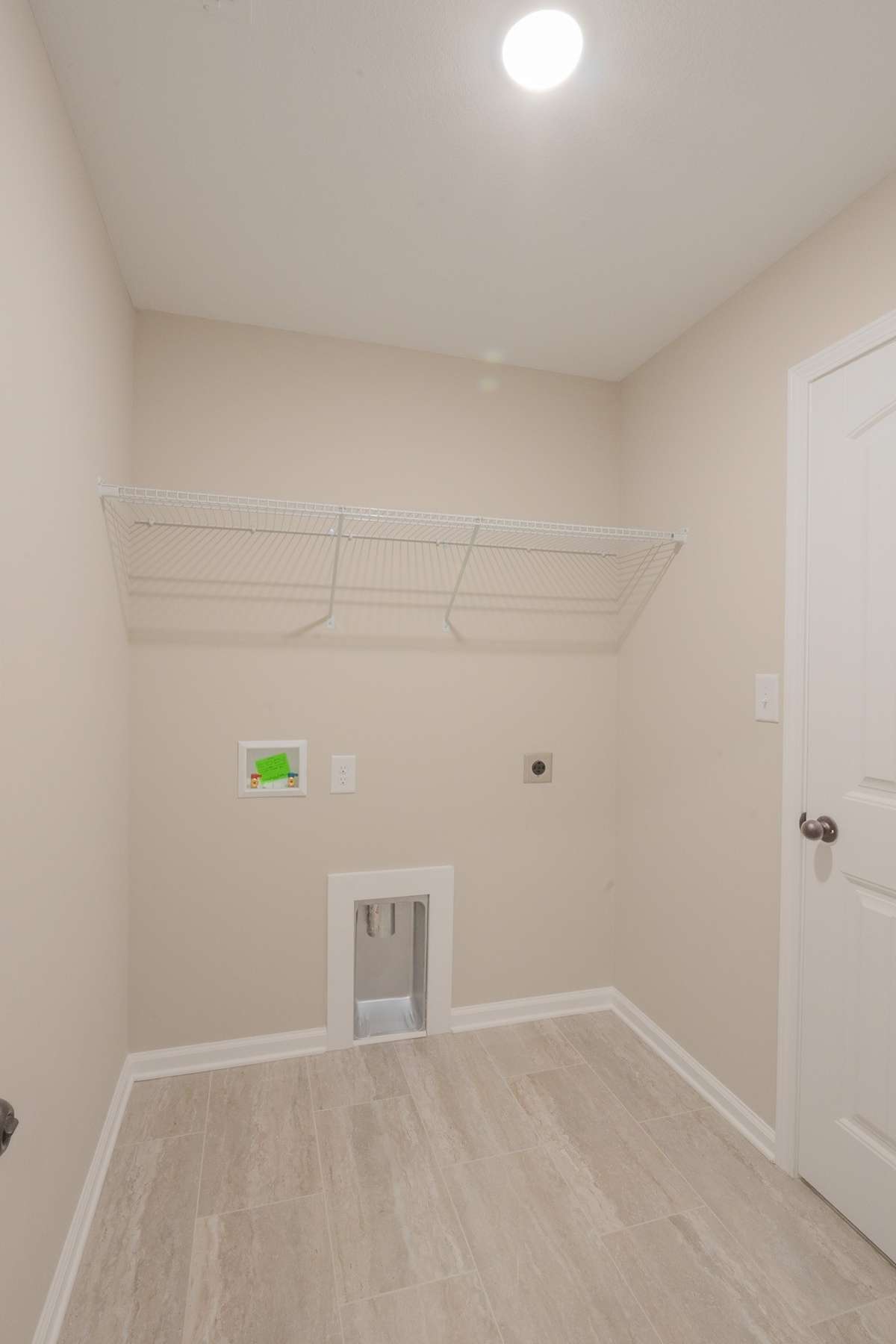 Large Laundry Room with Tile Flooring and Shelving! Laundry Connects to the Primary Closet Hallway and The Main Hallway!