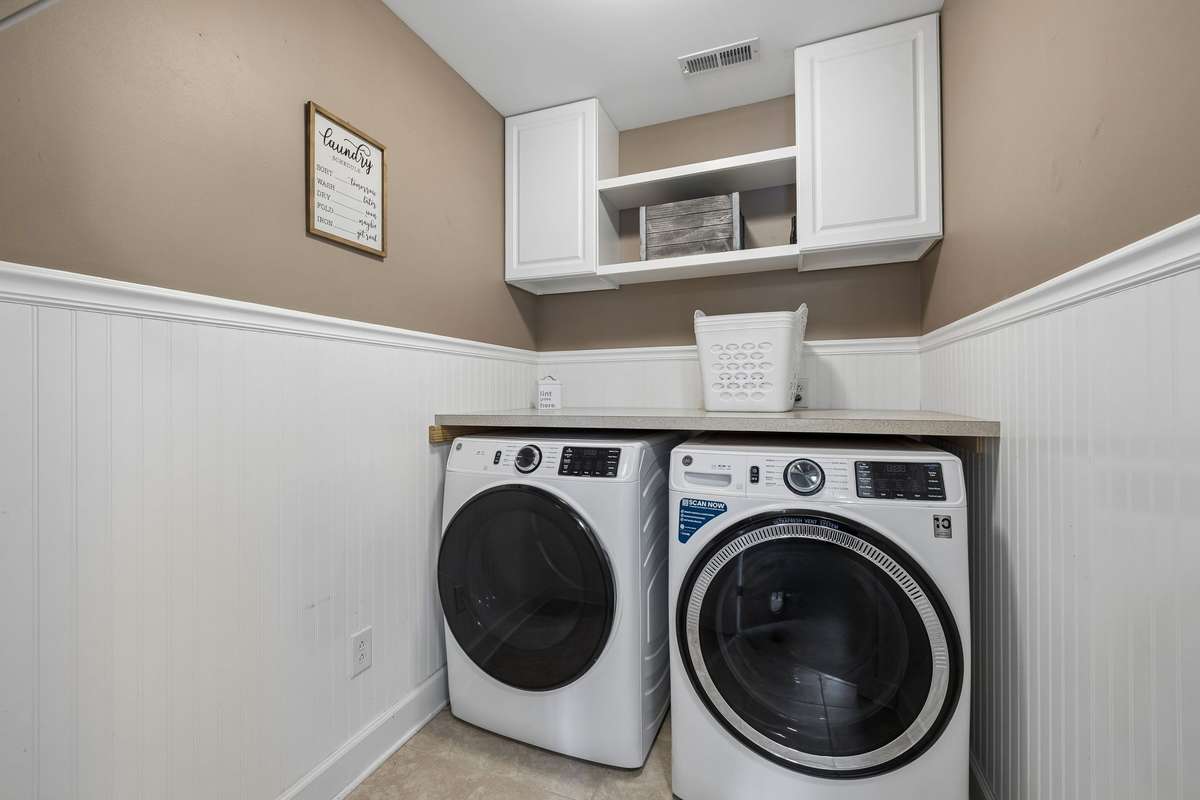 Large laundry room with storage cabinets and bead board trim.  Washer and dryer remains!!