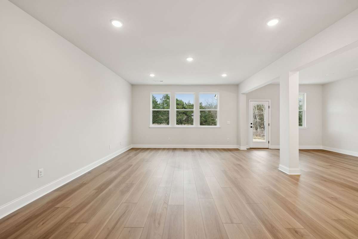 The great room offers plenty of space for comfortable living and entertaining. Large windows fill the room with natural light while providing peaceful views of the backyard - creating a serene and inviting atmosphere perfect for relaxing at home.
