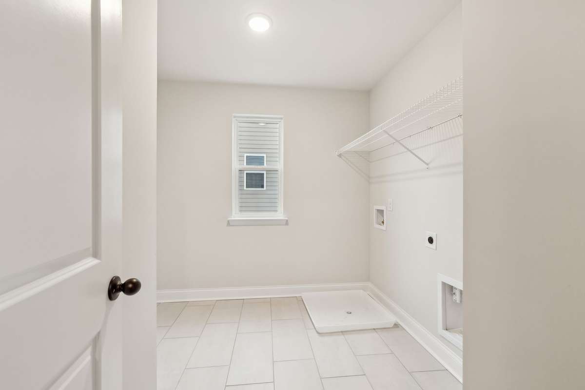 This roomy laundry area features durable tile flooring and offers ample space for a washer, dryer and folding area. Designed for both convenience and functionality, it makes household chores easier and more efficient.
