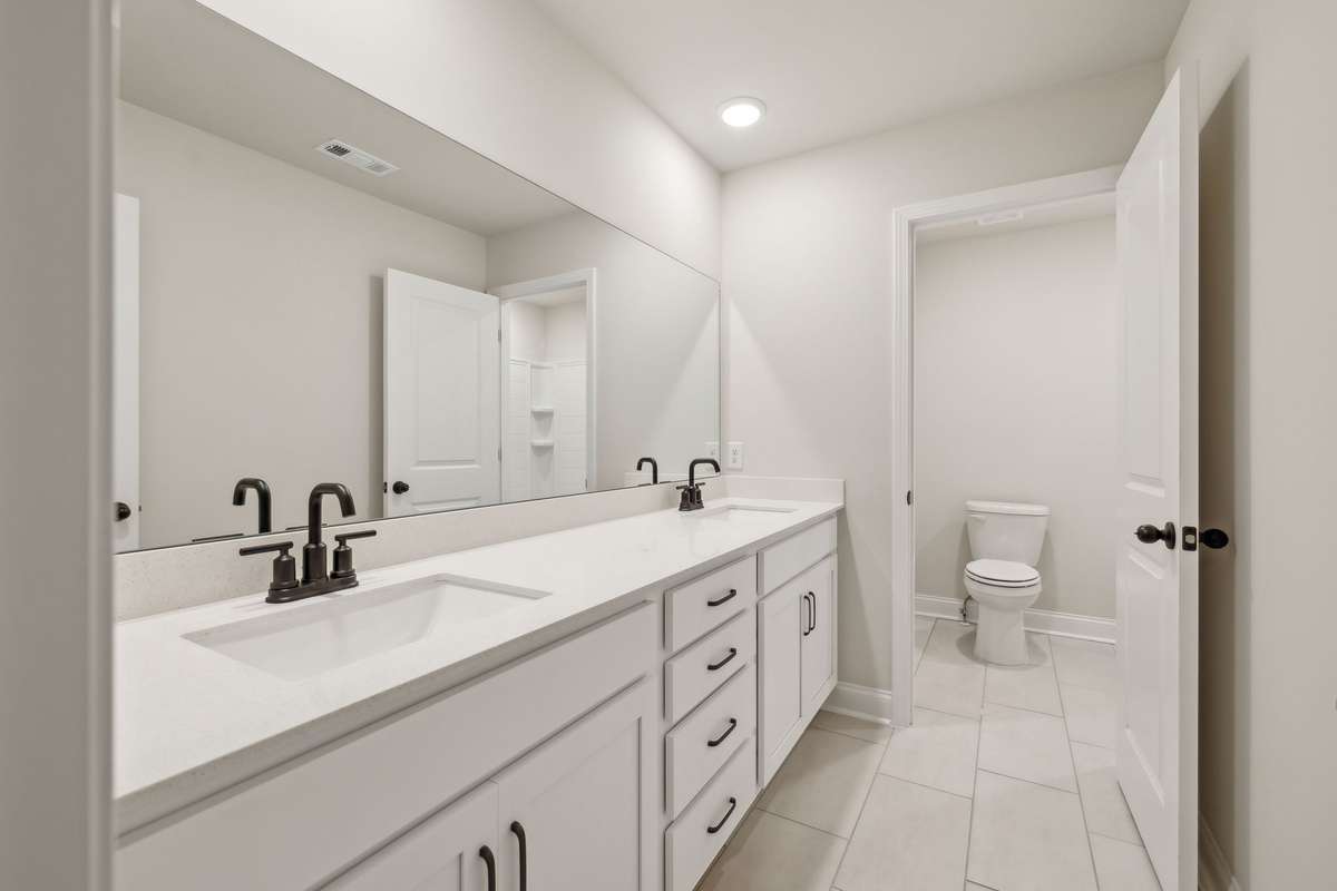 Bath #2 is located upstairs and features double sinks with quartz countertops, tile flooring and plenty of storage for towels, toiletries and more. Perfect for shared use, it combines modern finishes with everyday functionality.