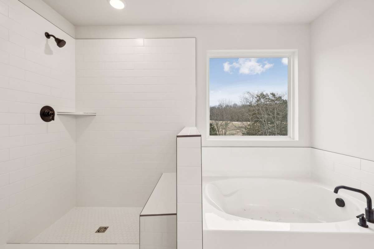 This elegant owner’s bath features a beautifully tiled shower and a separate garden tub, offering both style and relaxation. Designed for comfort and convenience, it’s the perfect spa-like retreat within the home.