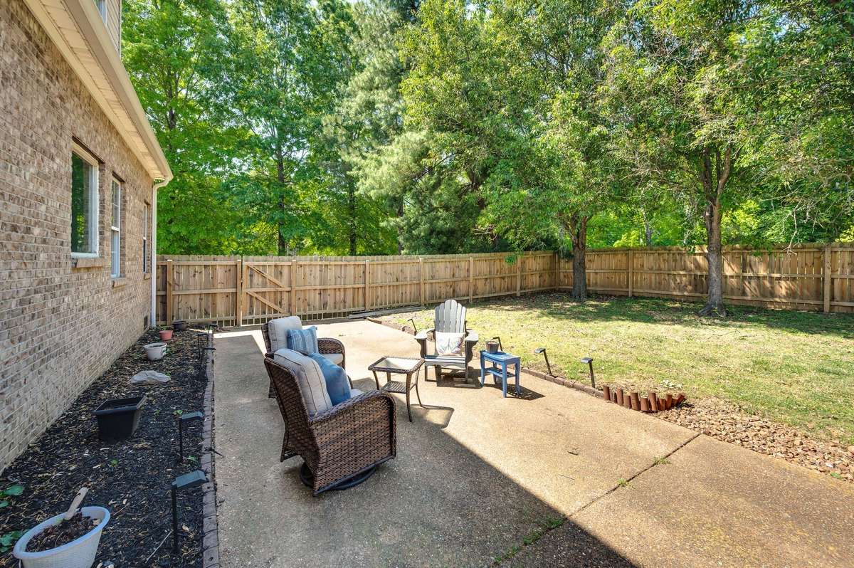 Greenery surrounds this large, peaceful backyard.