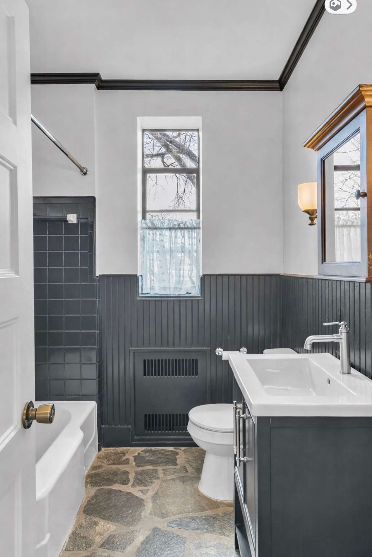 The classic black and white bath lives here which offers beadboard wainscoting and vintage  black tile.