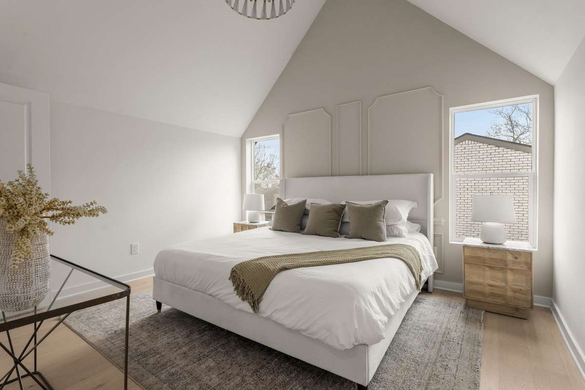 Primary bedroom with vaulted ceiling and wall trim detail
