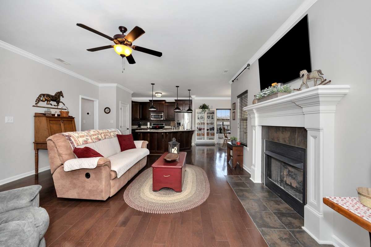 Living Room= wood flooring, crown molding, ceiling fan, fireplace