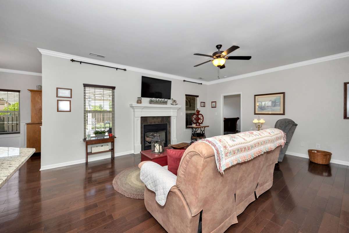Living Room- wood flooring, crown molding, ceiling fan, fireplace