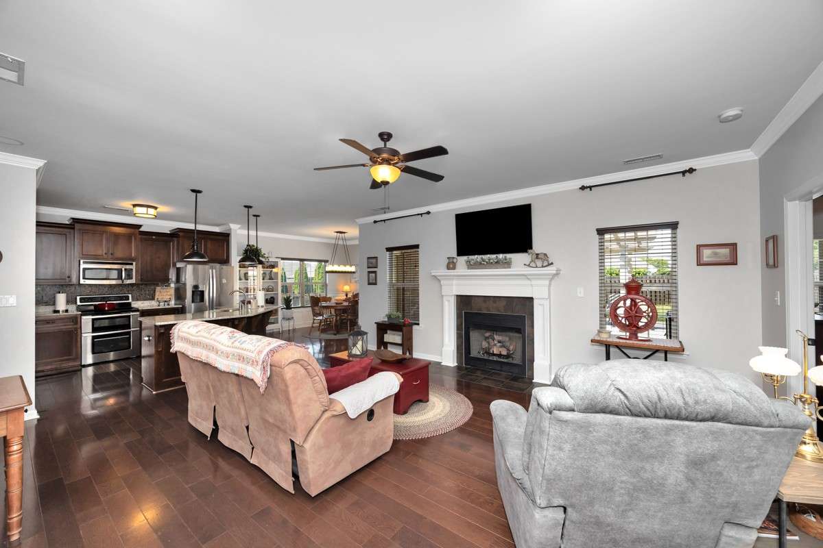 Living Room- wood flooring, crown molding, ceiling fan, fireplace