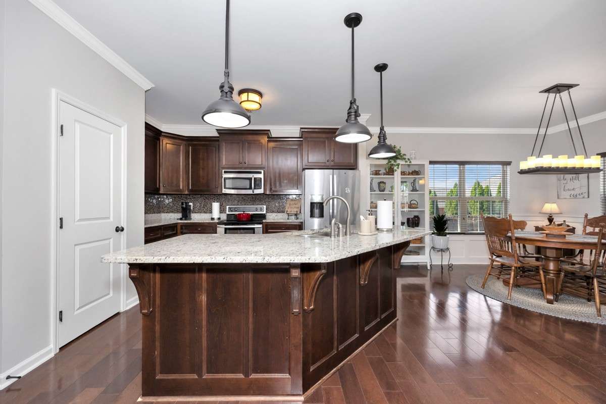 Kitchen- wood flooring, granite countertop, crown molding, bar seating, pantry, tile backsplash, stainless appliances:  refrigerator, microwave, stove, oven