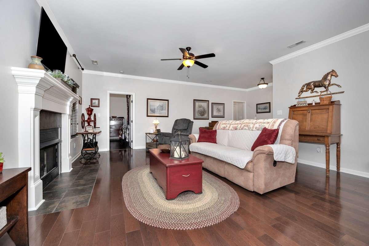 Living Room- wood flooring, crown molding, ceiling fan, fireplace