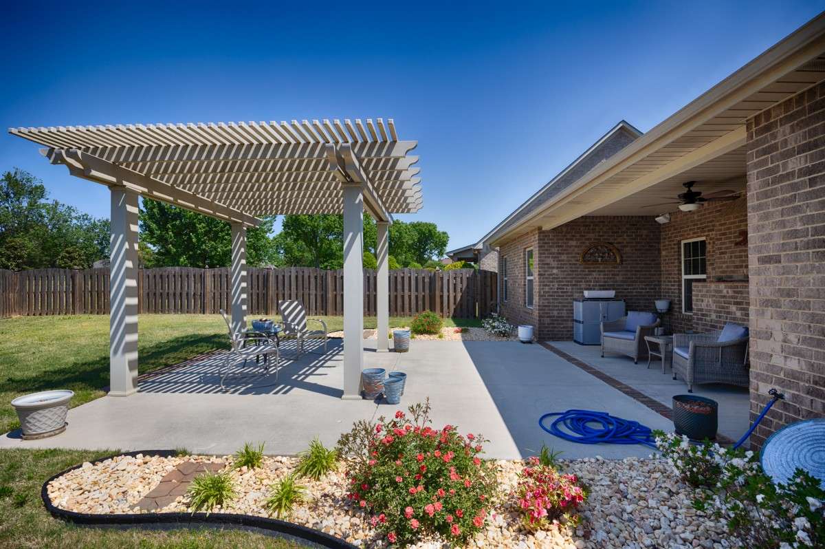 Back of house- Beautifully landscaped back yard with privacy fence, open patio with pergola, covered back porch with ceiling fan
